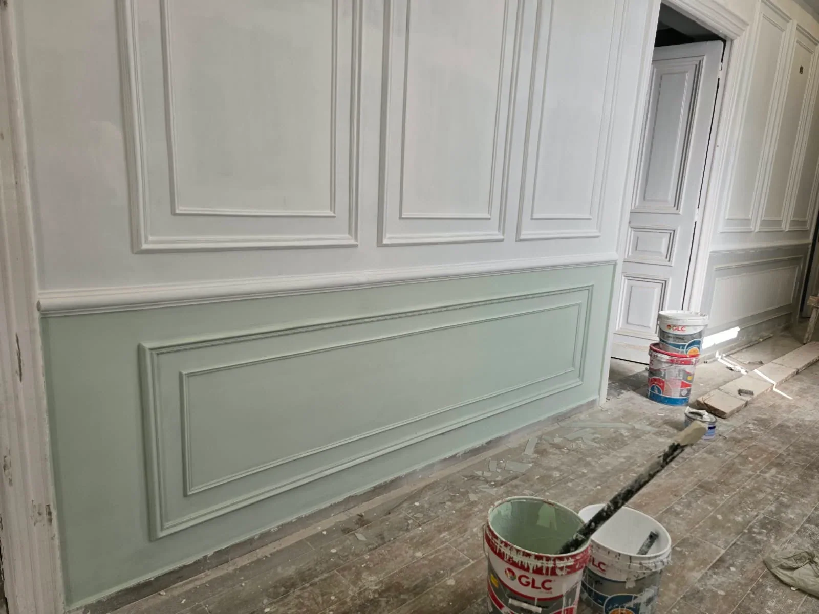 Wall mouldings being painted white and pale green before floor completion