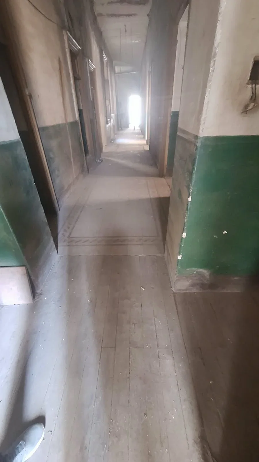 Corridor in its earlier condition, with green paint and worn timber flooring