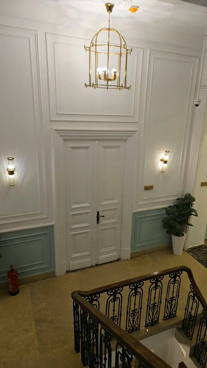 Finished stair landing with wall mouldings, a hanging lantern and metal balustrade