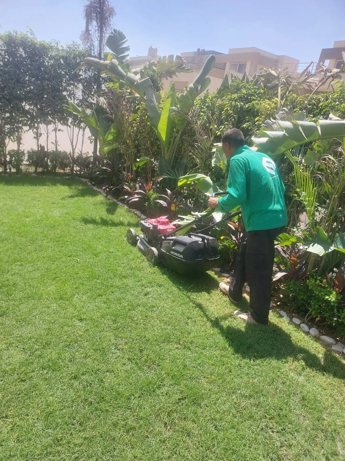Mowing the lawn along a planted bed with stone edging